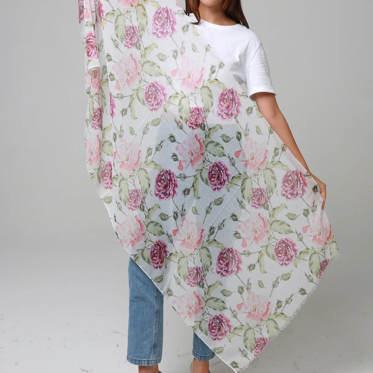 Woman holding a floral scarf with pink roses on a plain background