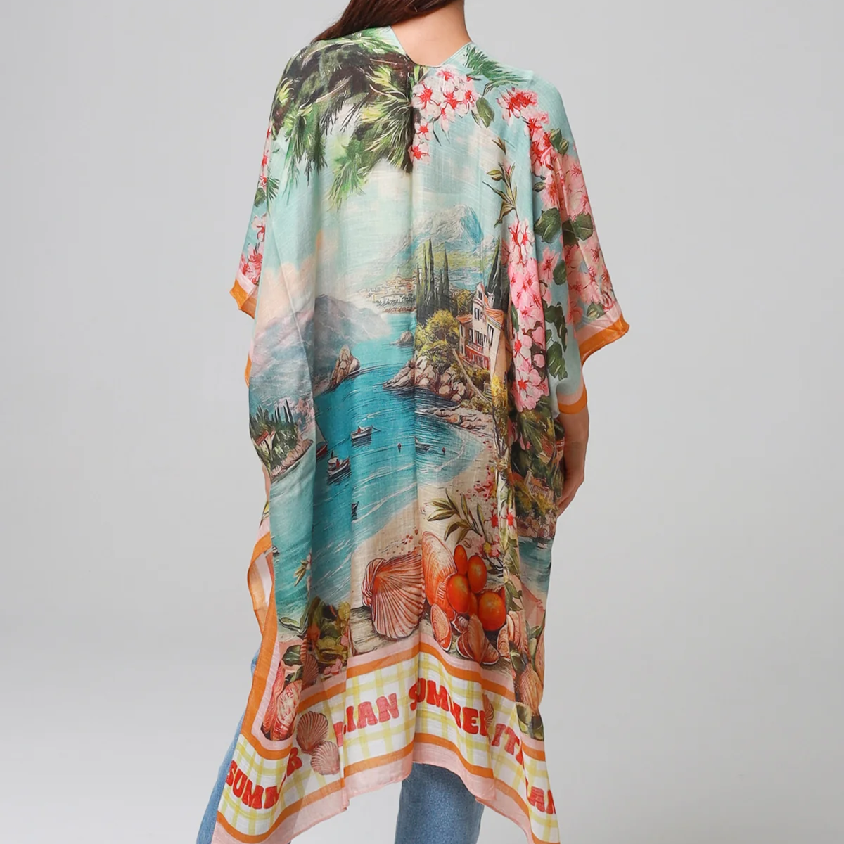 Woman wearing a colorful kimono-style garment with a scenic print on a plain background