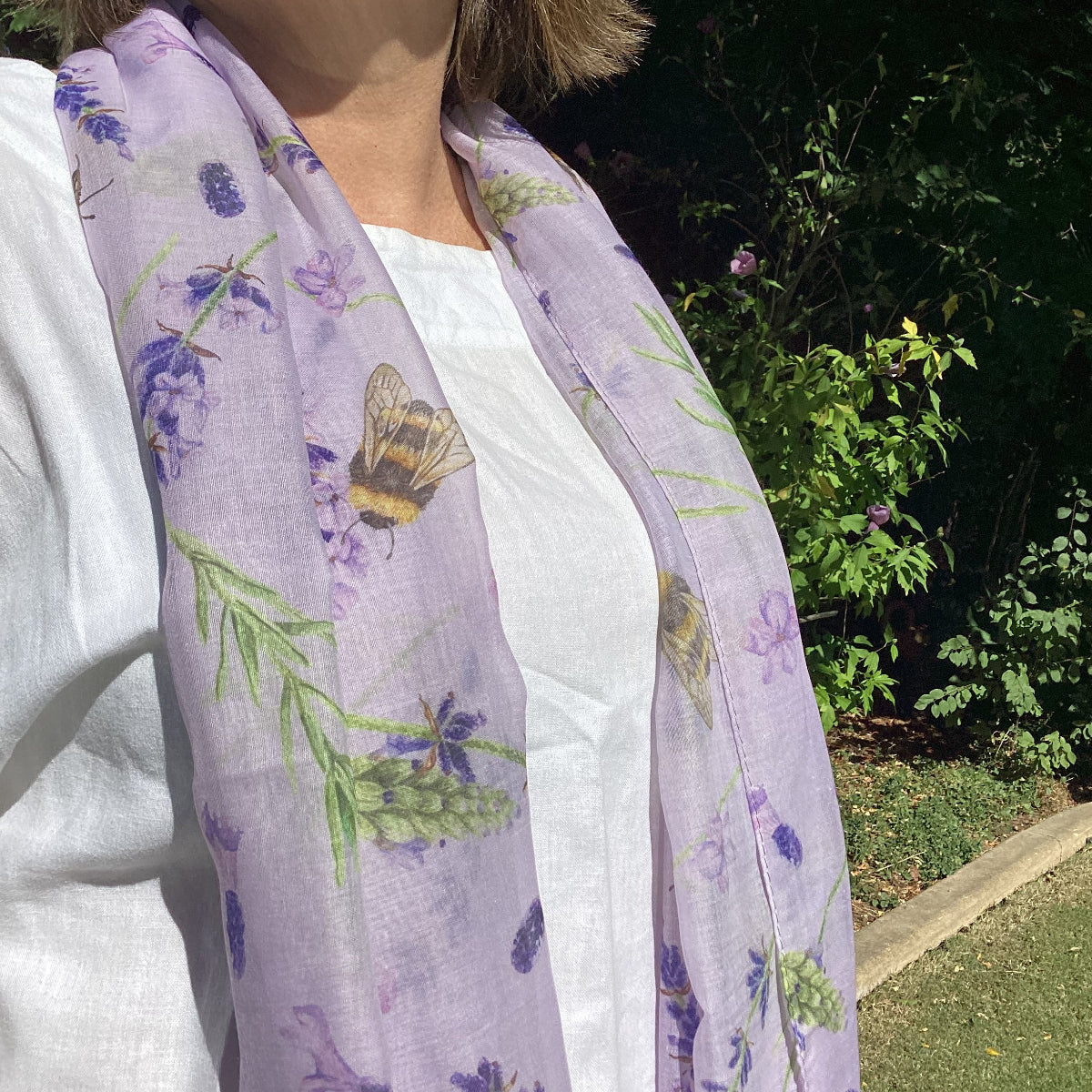 Woman wearing a purple floral-patterned garment with bees and flowers