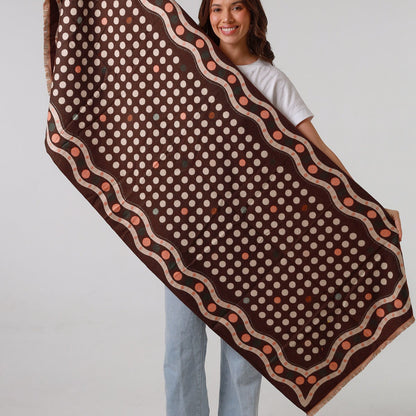 Woman holding a large brown and beige patterned fabric against a white background