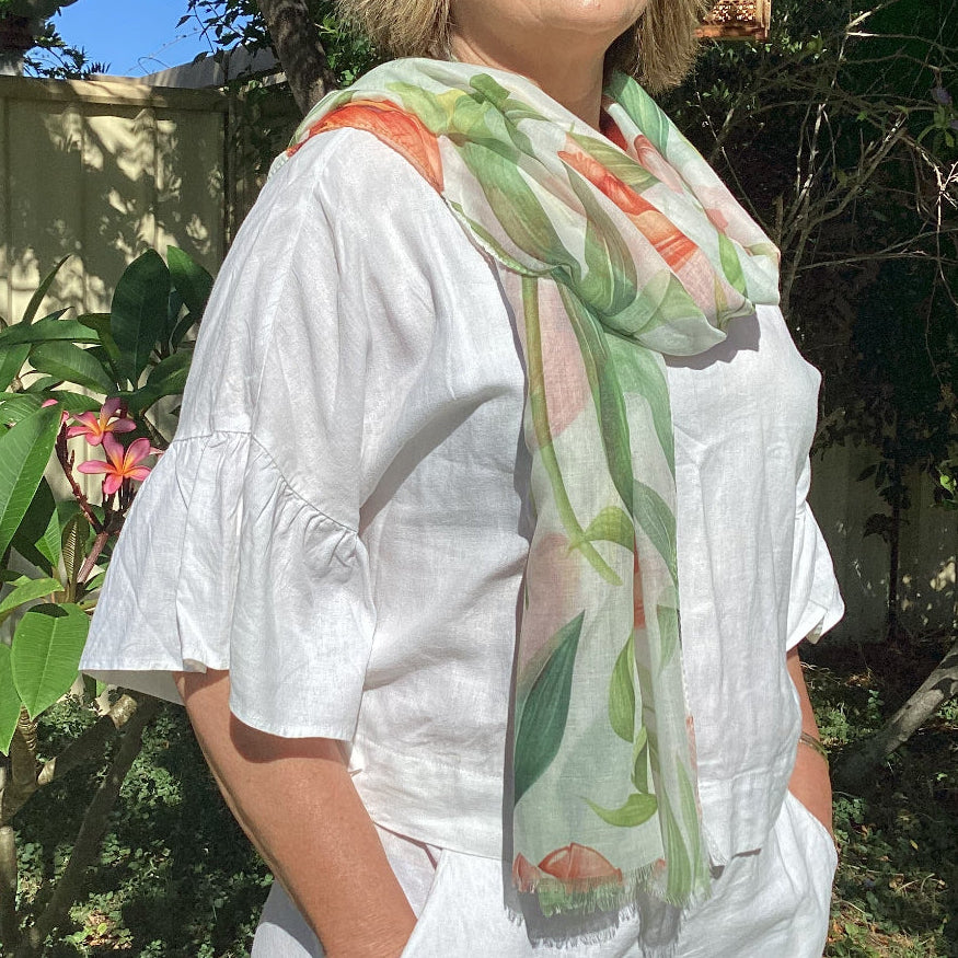 Woman wearing a white outfit with a floral scarf outdoors with sunglasses on.