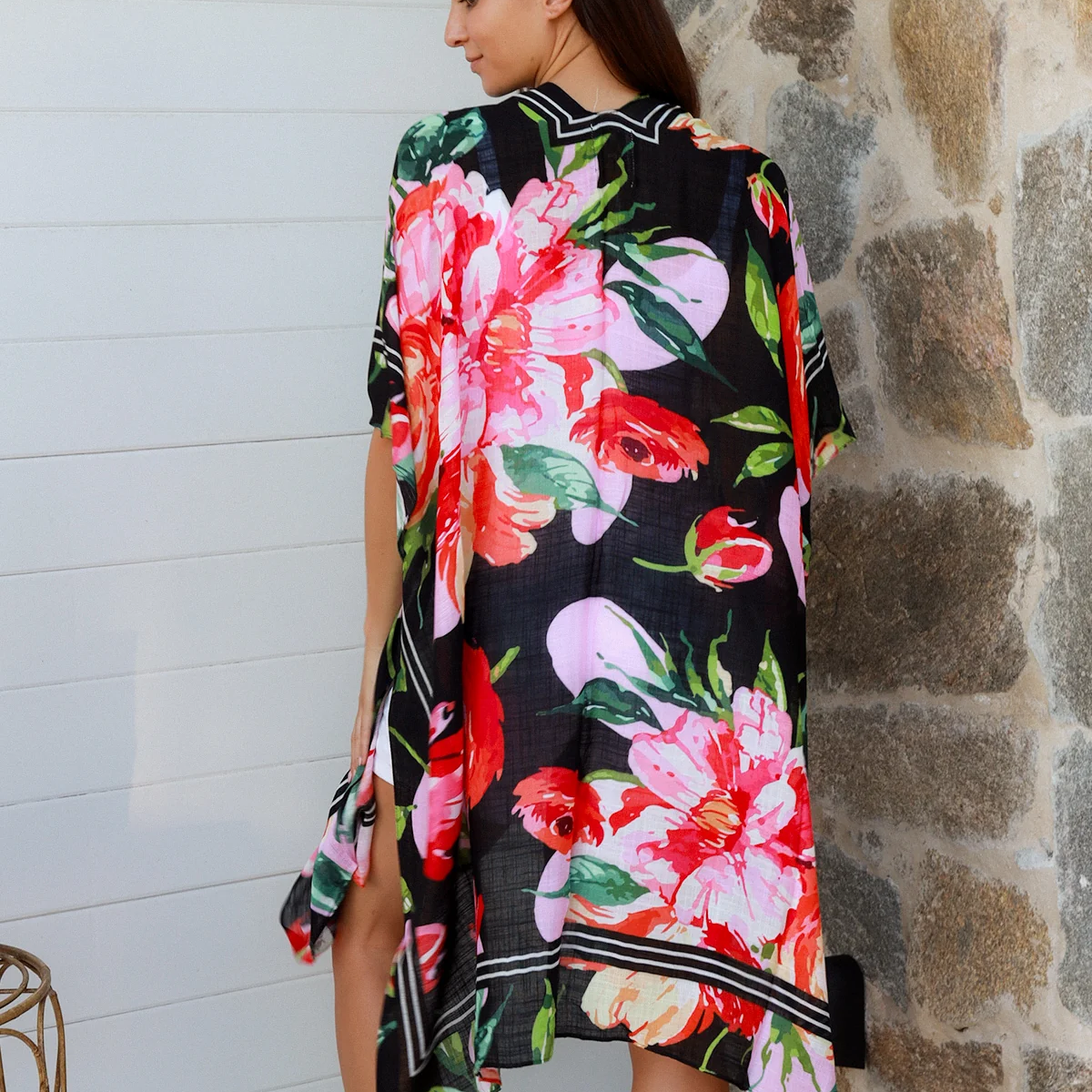 Woman wearing a floral kimono against a stone wall.