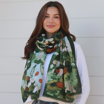 Woman wearing a green floral scarf, white shirt, and blue jeans against a white background