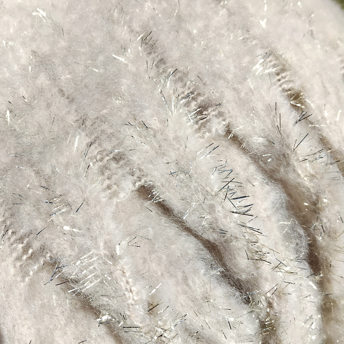 Close-up of a textured cream scarf with gold glitter fibers