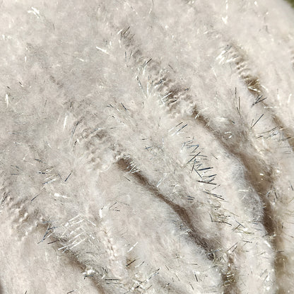Close-up of a textured cream scarf with gold glitter fibers