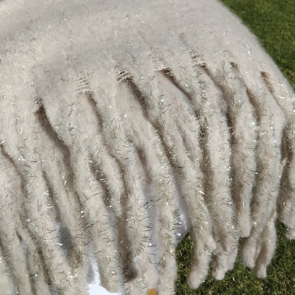 Close-up of a fluffy cream scarf with chunky tassels that is draped over a chair
