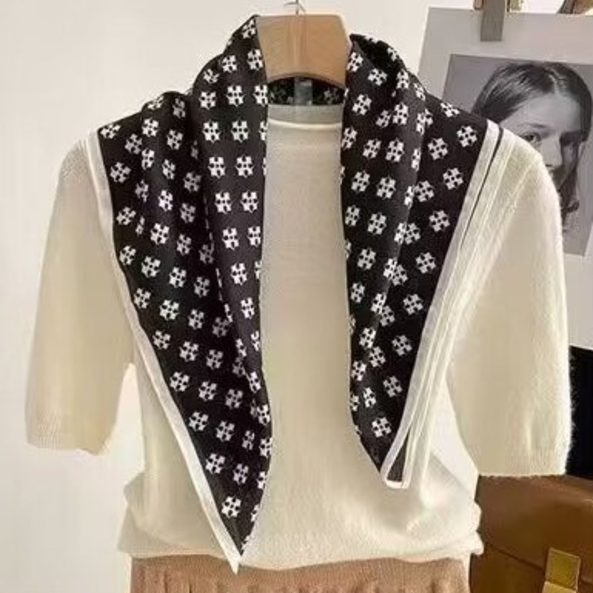 Black floral patterned scarf draped over a white outfit on a hanger.