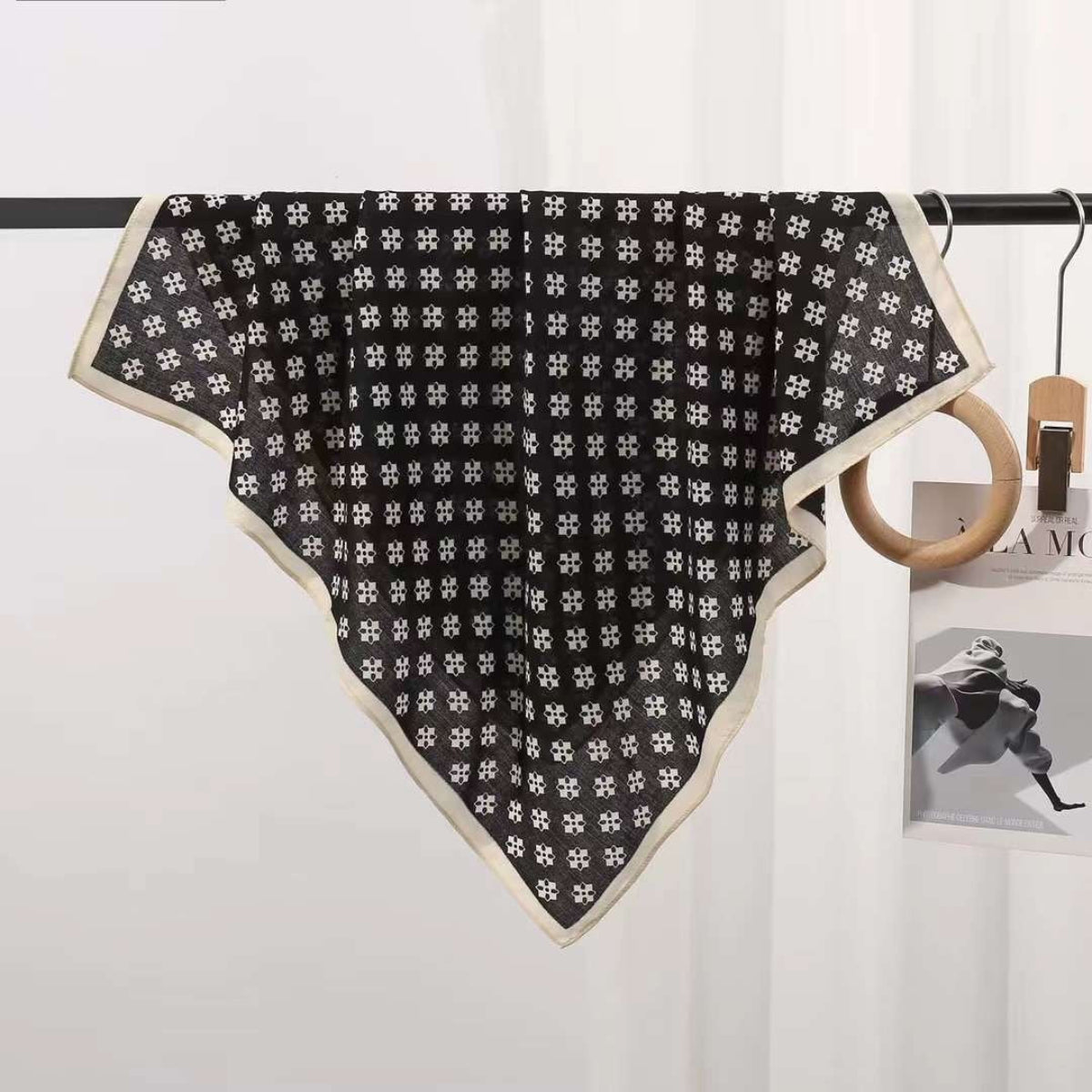 Black and white patterned scarf on a hanger against a white background.