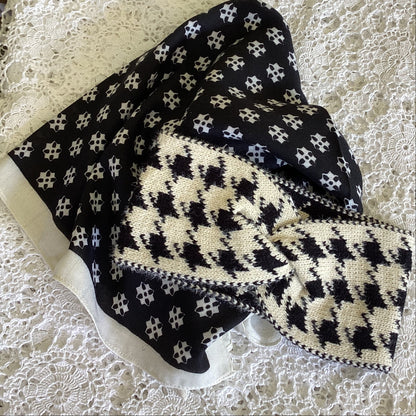 Black and white patterned scarf and a knitted cream and black herrongbone patterned headband on a lace background