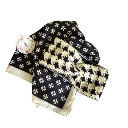 Black and white patterned scarf with a ream herringbone headband on floral tissue paper