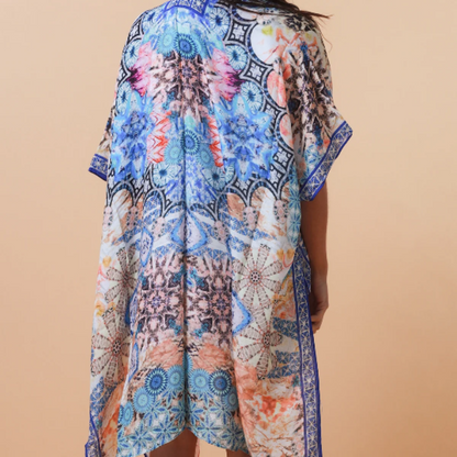 Woman wearing a colorful patterned kimono-style garment against a beige background