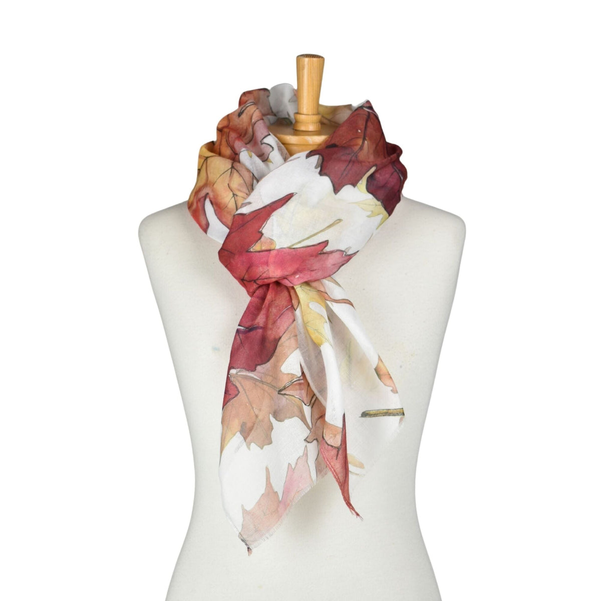 Colorful scarf with leaf pattern draped over a mannequin on a white background
