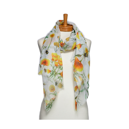 a pretty scarf that has a white background and yellow marigold and poppy flowers with bees amongst green foilage.