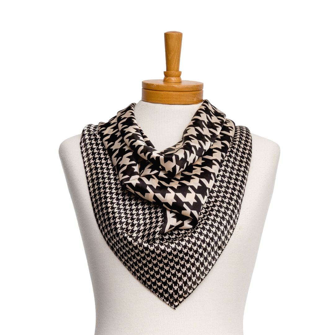 a square ladies scarf that has a large houndstooth pattern in the middle with a smaller houndstooth pattern as a border in black and cream.