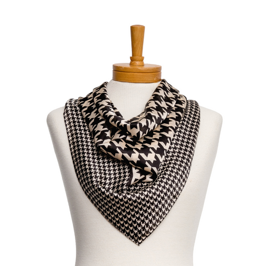 a square ladies scarf that has a large houndstooth pattern in the middle with a smaller houndstooth pattern as a border in black and cream.