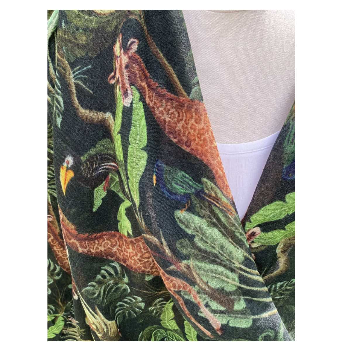 A white top with  a jungle-themed pattern scarf featuring animals and foliage.