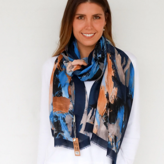 Woman wearing a colorful scarf with a white shirt and blue jeans against a plain background