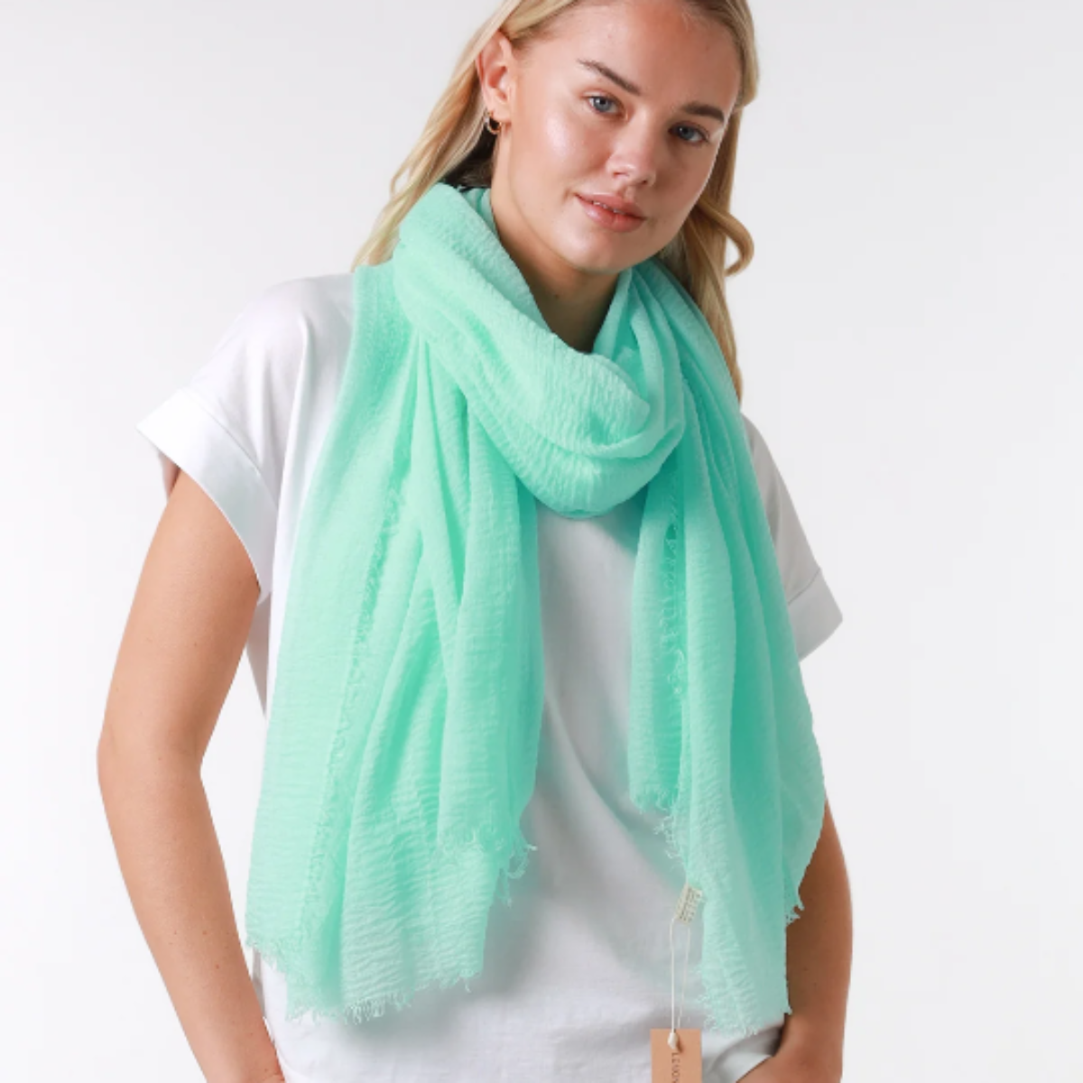 Woman wearing a light green scarf with a white background