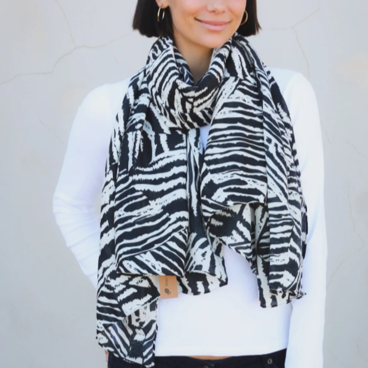 a lady wearing a black and white scarf that has an abstract linear pattern