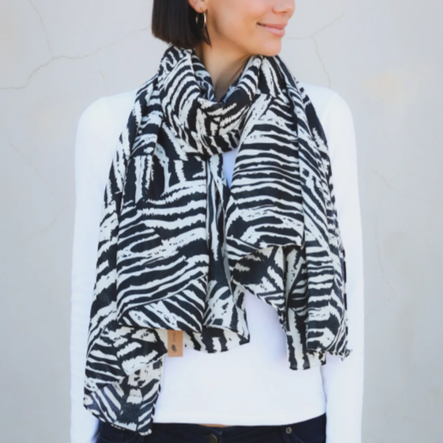 a lady wearing a black and white scarf that has an abstract pattern