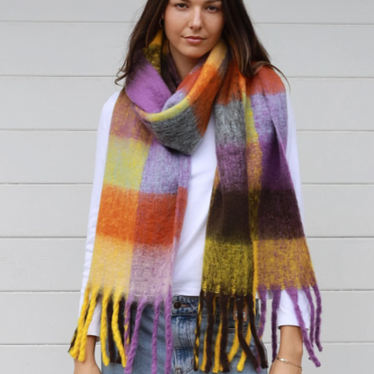 Woman wearing a colorful plaid scarf against a light background