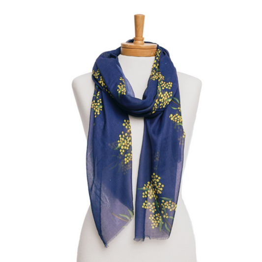 A ladies scarf made from lightweight cotton that has  navy blue background and yellow Wattle flowers in bunches and green leaves