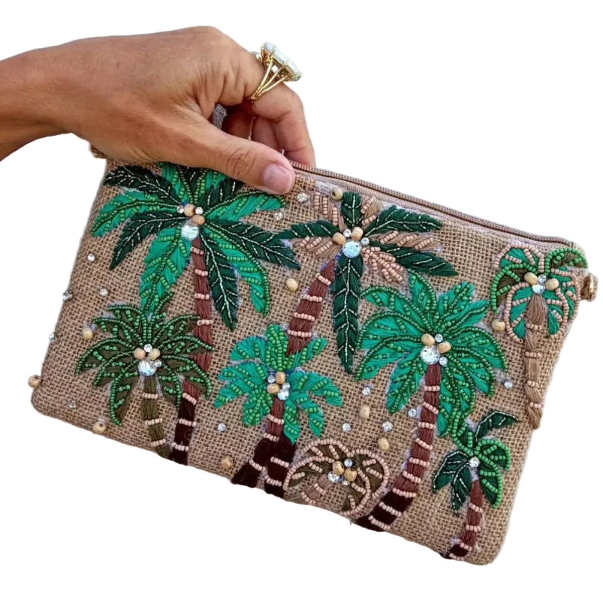 A hand holds a small zip pouch decorated with embroidered palm trees and small pearl-like beads on a tan woven background, against a plain light wall.