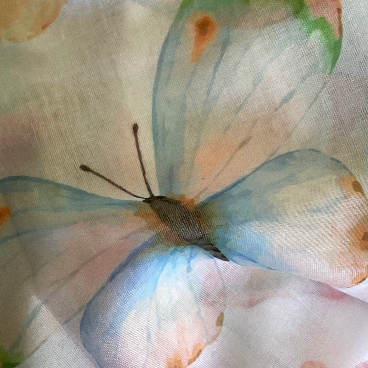 Close-up of a butterfly design on fabric with watercolor-like colors.
