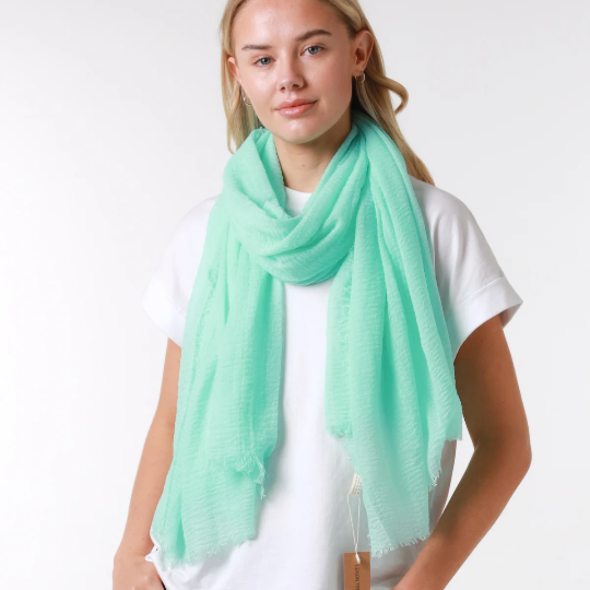 Person wearing a light green scarf, white shirt, and blue jeans on a white background