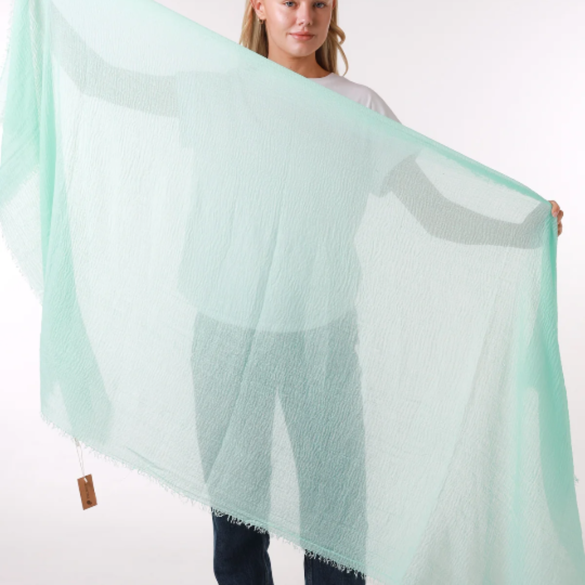 Person holding a large light green scarf against a white background