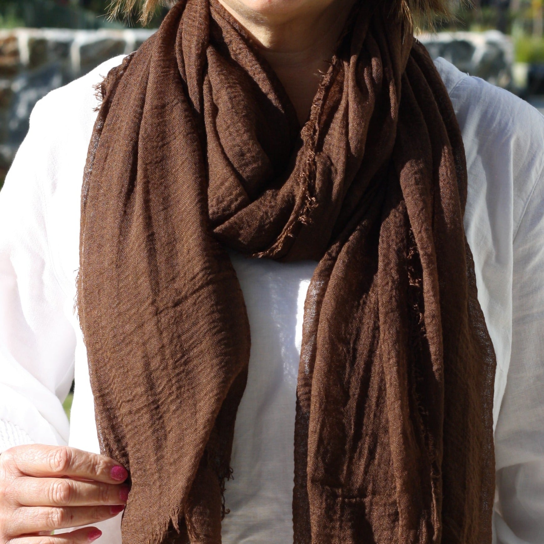 a dark brown ladies scarf that is plain but has a textured weave and frayed edges on all sides.