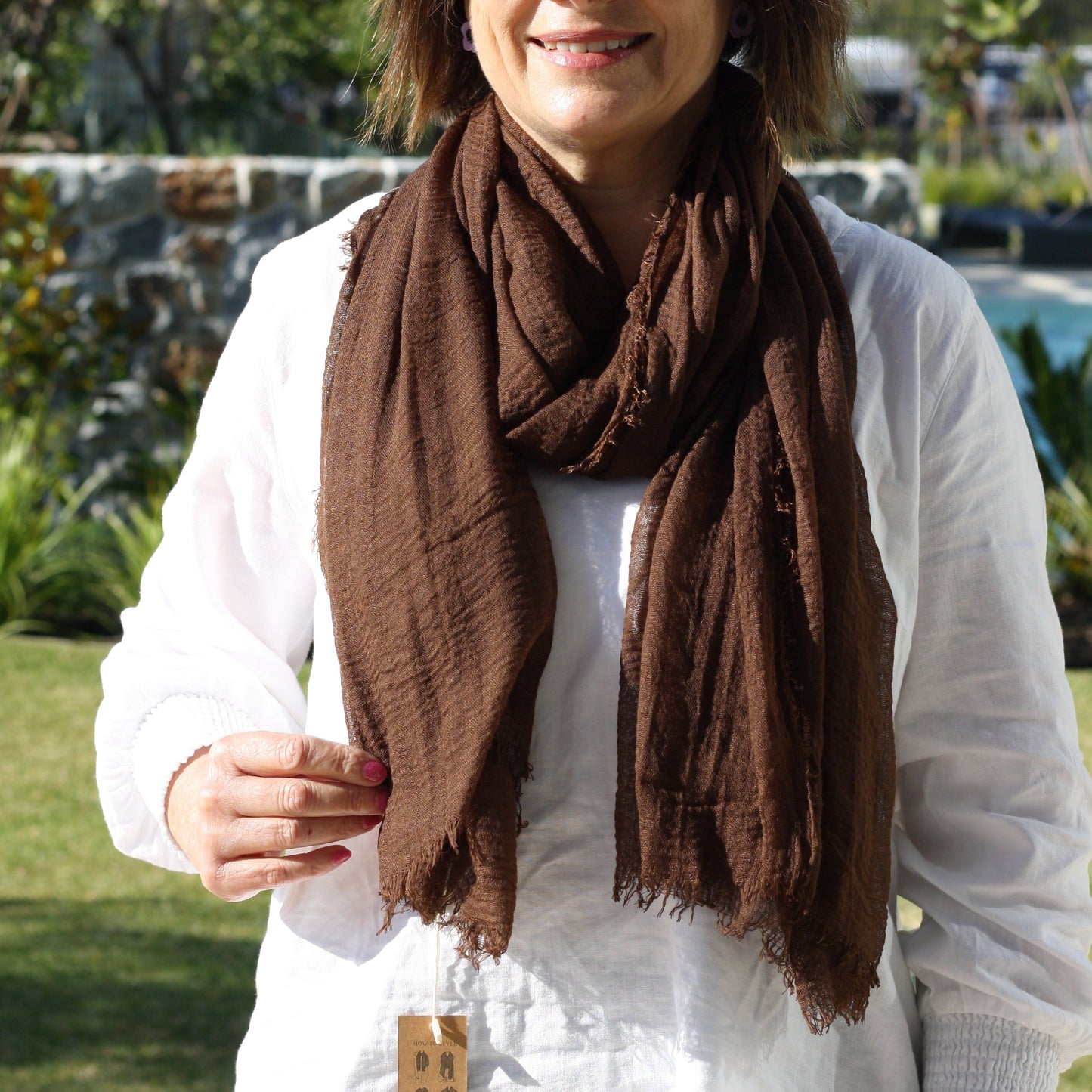 a lady wearing a dark brown coloured plain scarf that has a textured weave and a frayed edge