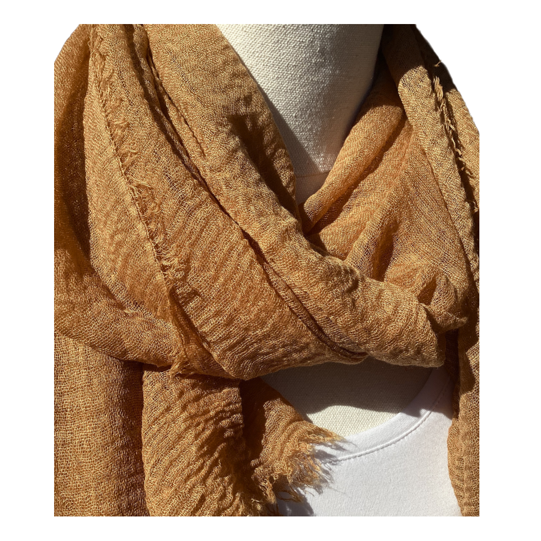 a close up view of a light brown coloured scarf that has a textured weave.