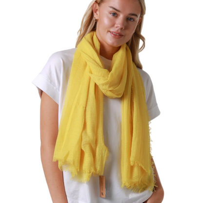 Woman wearing a yellow scarf, white t-shirt, and blue jeans on a white background