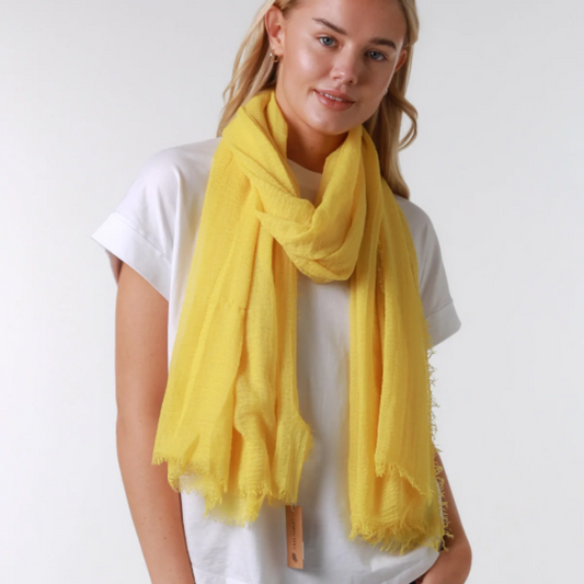 Woman wearing a yellow scarf, white t-shirt, and blue jeans on a white background