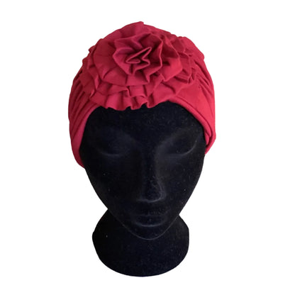 Red turban on a black mannequin head with a large flower at the front