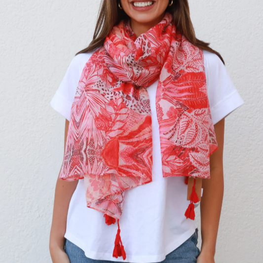 a lady wearing a scarf that has a leopard and jungle print in bright colours of red, pink and orange.