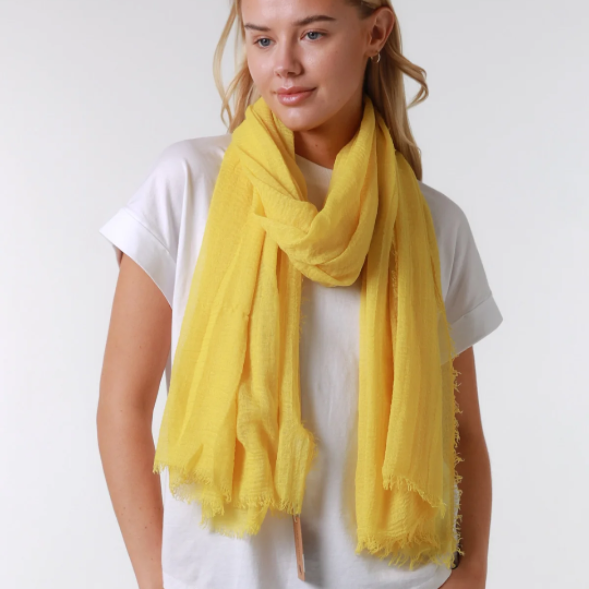 Woman wearing a yellow scarf and white shirt on a white background
