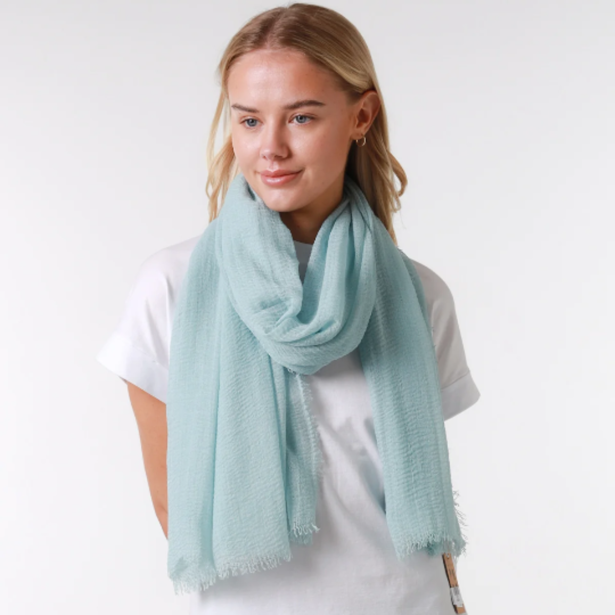 Woman wearing a light blue scarf over a white shirt on a white background