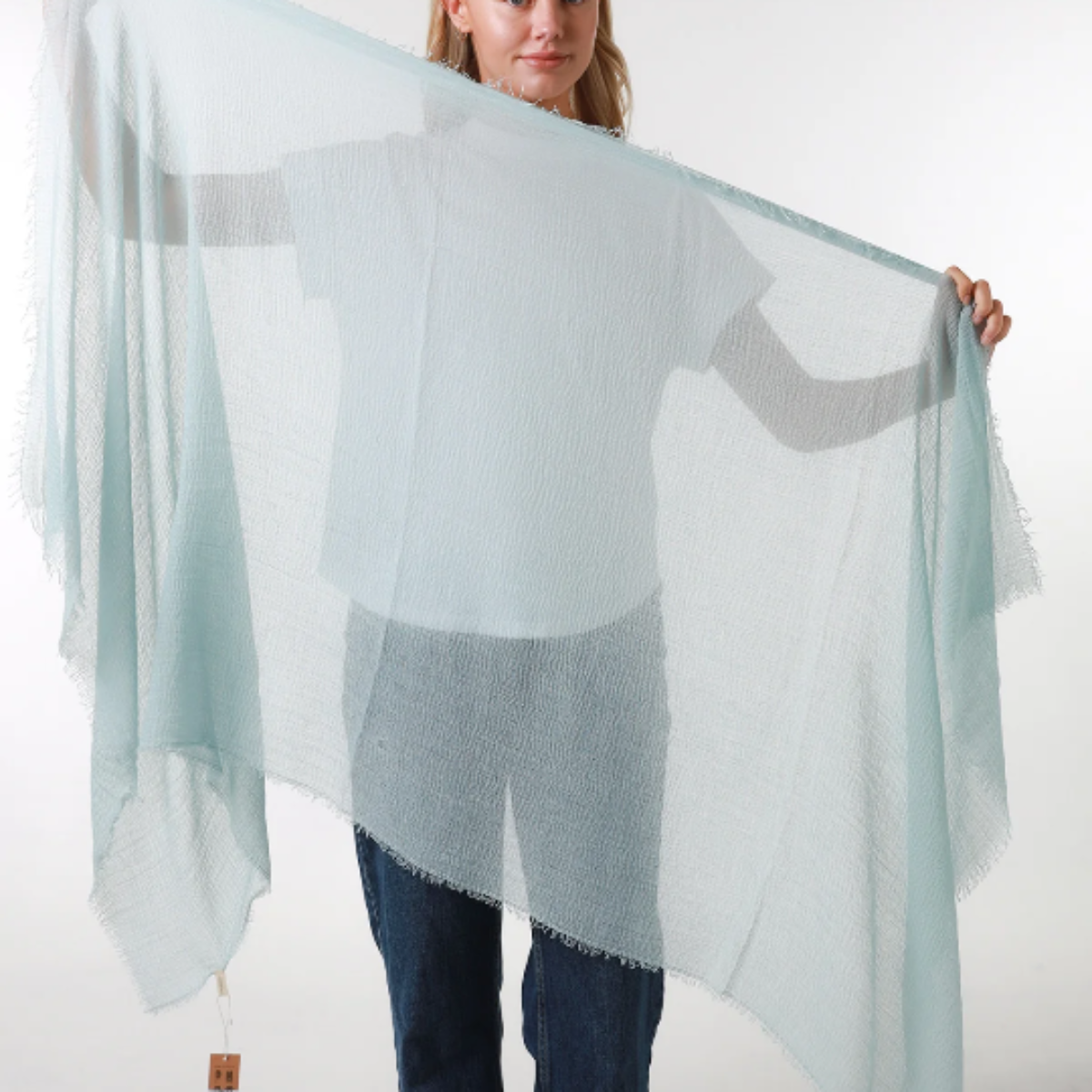 Woman holding a light blue scarf against a white background