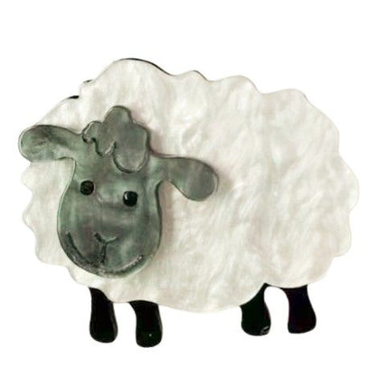 A decorative sheep brooch with a twhite pearl body, a gray face, and black legs, shown against a plain white background.