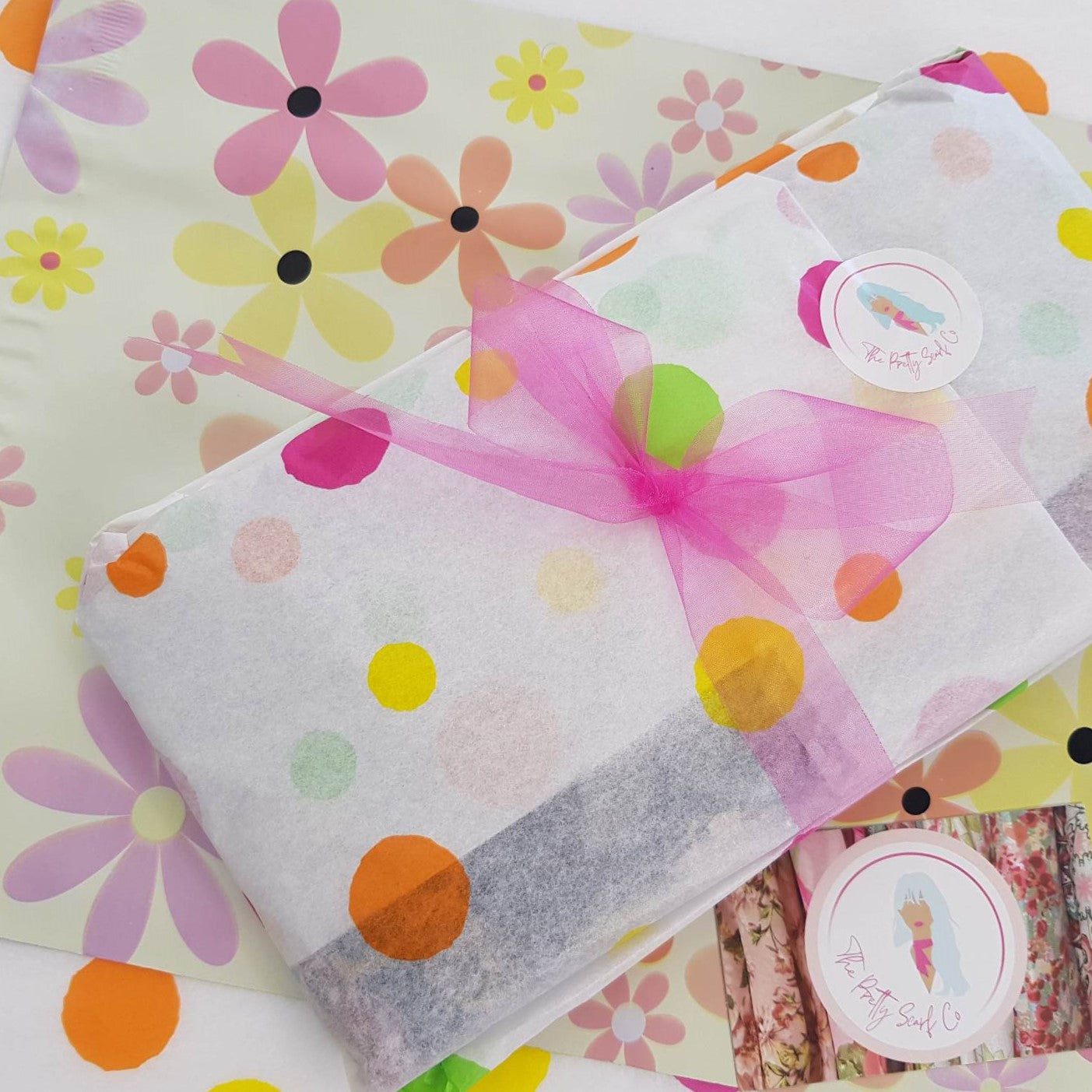 a pretty scarf wrapped in confetti tissue paper and tied with a bright pink ribbon