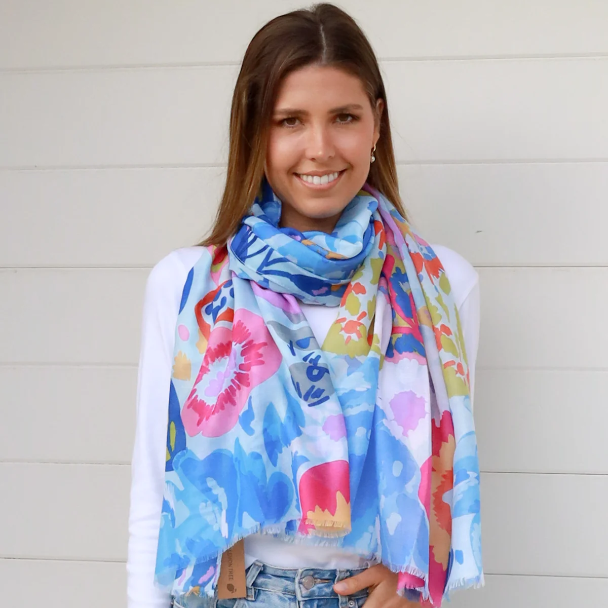 Woman wearing a colorful blue floral scarf with a white background