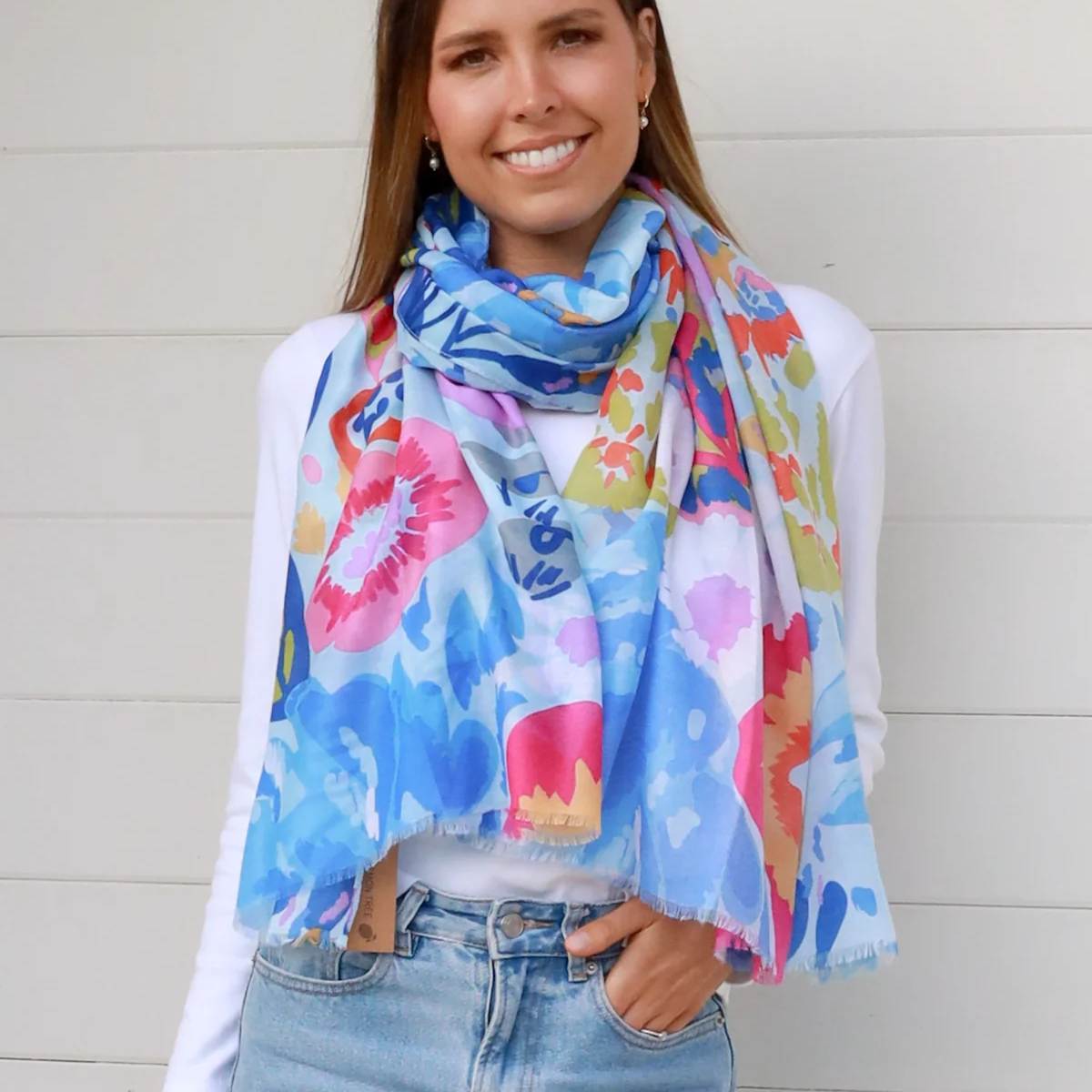 Woman wearing a colorful blue floral scarf against a plain background