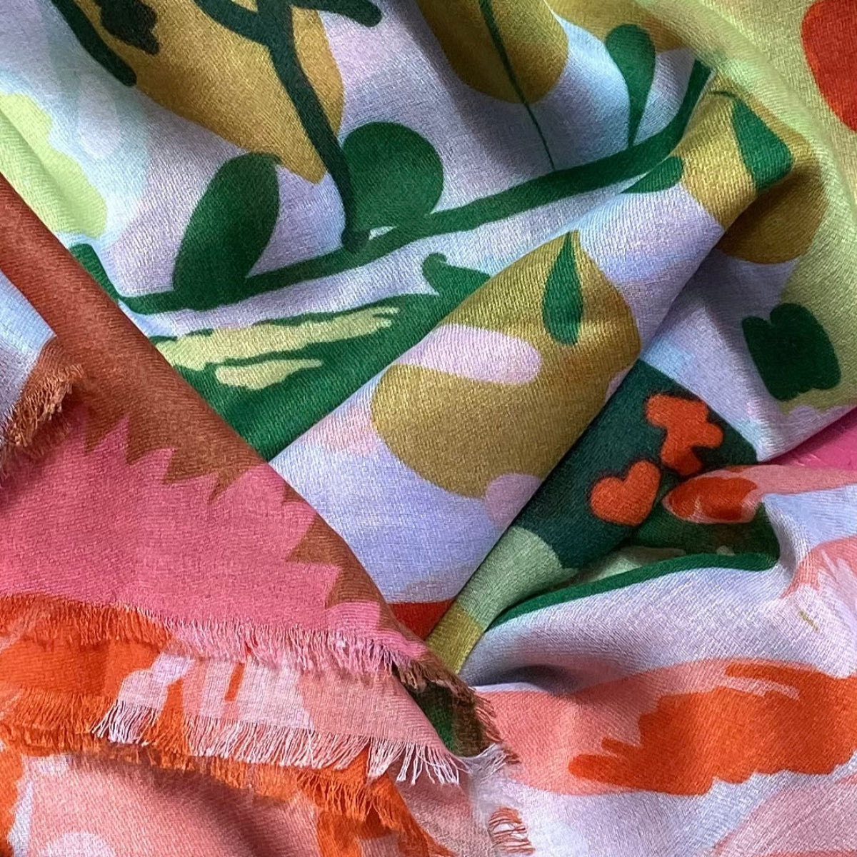 Close-up of a scarf with colorful floral patterns and frayed edges.