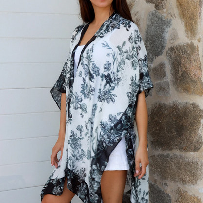 Woman wearing a floral cover-up against a stone wall.