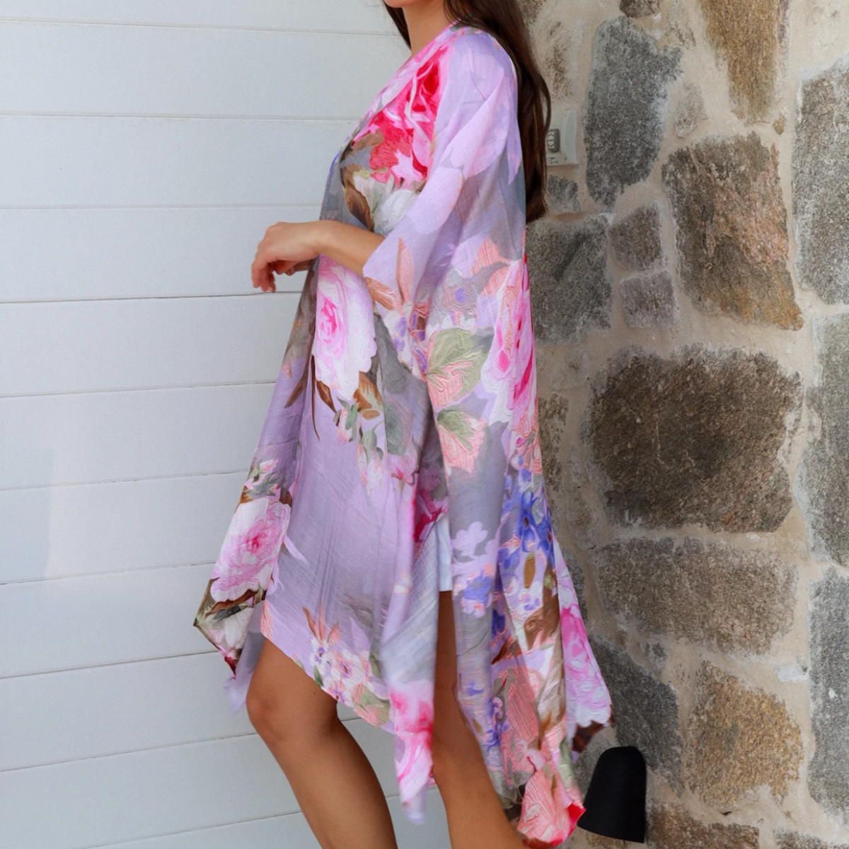 Woman wearing a floral kimono against a stone wall.