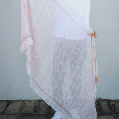 Woman holding a white and taupe brown scarf against a plain background