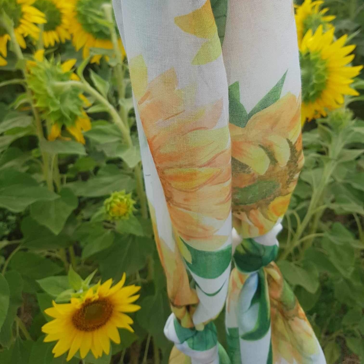 a scarf that has sunflowers and bumble bees in front of a field of sunflowers