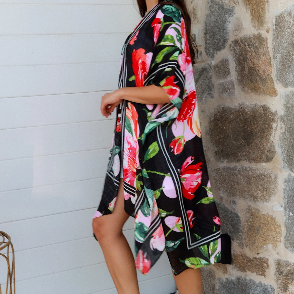 Woman wearing a floral kimono against a stone wall.
